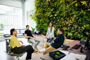 A-group-of-colleagues-sitting-in-front-of-a-large,-green-plant-display