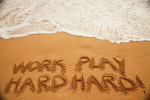"Work-Hard-Play-Harder"-written-in-beach-sand.
