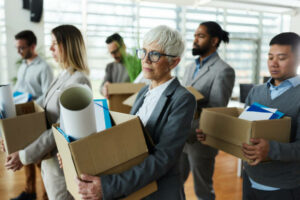 Large-group-of-displeased-employees-carrying-carton-boxed-with-their-belongings-after-being-sacked-from-their-jobs.