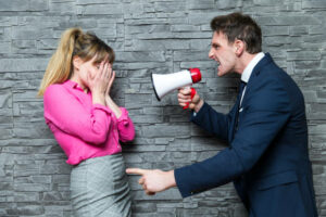 A-employer-in-a-suit-with-tie-yells-at-his-female-employee-with-a-megaphone.