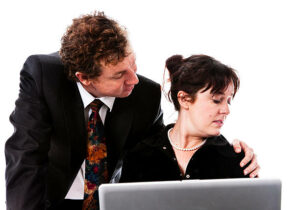 Male-employee-with-his-arm-around-female-employee-who-looks-distressed.