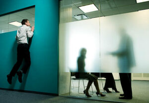 Employee-listening-in-to-a conversation-over-a-partition.-Can-your-boss-spy-on-you?