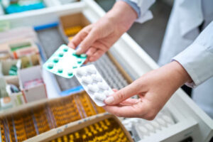 Pharmacists-holding-pills-in-hands-above-drawer-with-medicines. 