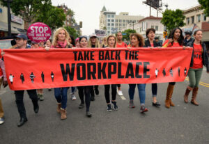 Sexual-Assault-and-harassment-at-Work.-Marching-with-take-back-the-workplace-banner.