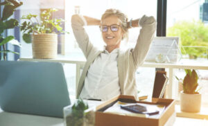 Employee-feeling-accomplished-and-enjoying-a-break-to-stretch-with-hands -behind-her-head-in-an-office.